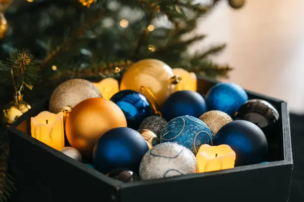Christmas balls still in the storage box, ready to be hung on the tree with other holiday decorations. Golden and blue Christmas balls packed. Storage of new