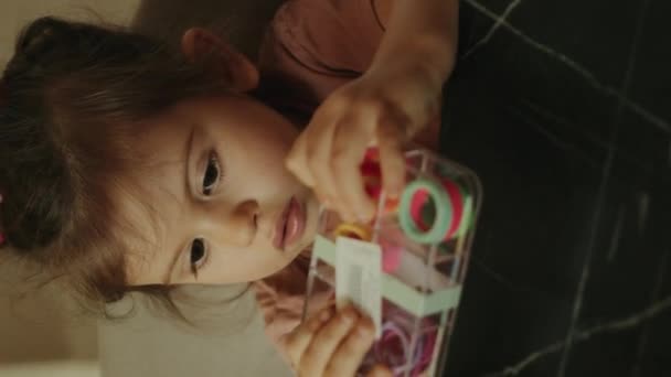 Очаровательная Маленькая Девочка Открывает Коробку Разноцветных Резинки Волос Детская Комната — стоковое видео