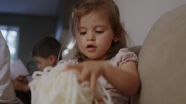 ソファーでアクティビティを脅かすために弦で遊ぶ小さな子供の少女 モータースキル開発 — ストック動画