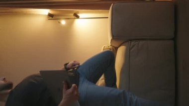 Sakallı yakışıklı adam evdeki kanepede bilgisayar kullanıyor. Rahat bir oturma odası. Evden çalışan serbest çalışan biri. Sosyal ağlar kullanılıyor.