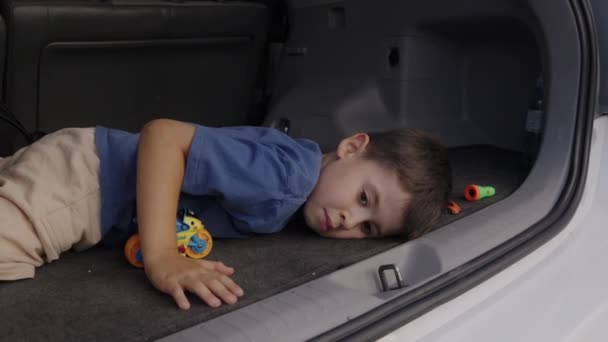 Мечтательный Ребенок Голубой Футболке Лежащий Животе Автомобильном Багажнике Задумчиво Глядя — стоковое видео