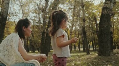 Genç anne ve kızı yaz kıyafetleri içinde gülümsüyor ve birlikte zaman geçiriyorlar. Güzel anne ve çocuk dışarıda. Çocuklu ebeveyn birlikte vakit geçirir.