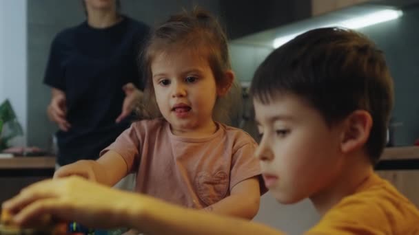 Küçük Çocuklar Mutfak Masasında Oturup Oyuncaklarla Oynayarak Eğleniyorlar Evde Yaratıcı — Stok video