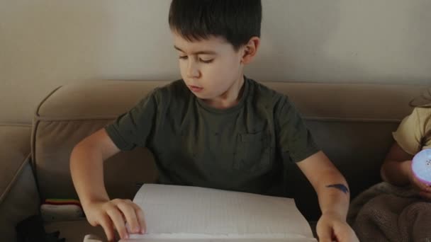 Lähikuva Iloinen Poika Istuu Sohvalla Kirjallisesti Kynällä Istuu Sohvalla Kotona — kuvapankkivideo