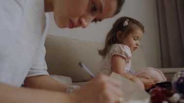 Sevimli küçük kız ve anne hafta sonları evde oturma odasında tuval dikerek iyi vakit geçiriyorlar. Aile aktivitesi konsepti. Çocuk gelişimi, aile