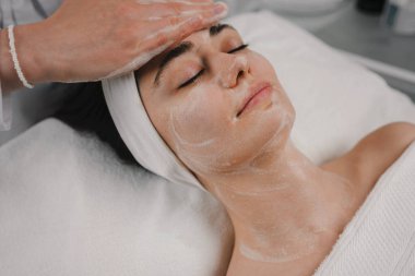 Genç bir kadın güzellik salonunda kozmetik cilt bakımı ve tedavi görüyor. Spa kozmetolojisi ve sağlık rahatlama kavramı.