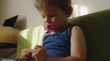 Kanepede portatif video konsoluyla video oyunu oynayan küçük bir kız.