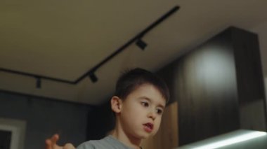 Çocuk evin içinde durup parmaklarıyla işaret ediyor. Neşeli çocuk, evde eğleniyor..