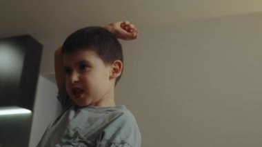 Çocuk tek başına oynuyor, bağırıyor ve elleri havada el kol hareketi yapıyor..