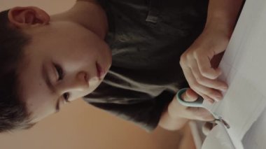 Küçük çocuk boş kağıttan şekiller kesiyor. Çocuklar yaratıcı olmak, hayal gücünü geliştirmek, yaratıcılık, bunu kendiniz yapın.