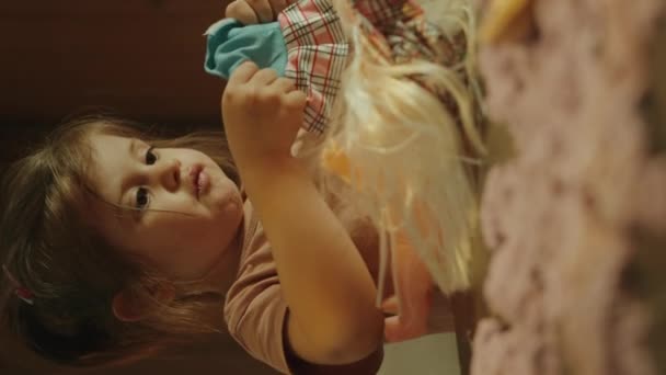 Mała Dziewczynka Siedzi Przy Stole Domu Ubierając Lalkę Bawiąc Się — Wideo stockowe