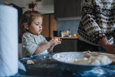Aile eğleniyor, modern mutfakta birlikte ev yapımı hamur işi hazırlıyorlar. Neşeli yaşlı nine, küçük tatlı torununla aşçılık becerilerini paylaşıyor..