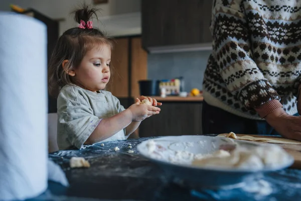 Aile eğleniyor, modern mutfakta birlikte ev yapımı hamur işi hazırlıyorlar. Neşeli yaşlı nine, küçük tatlı torununla aşçılık becerilerini paylaşıyor..