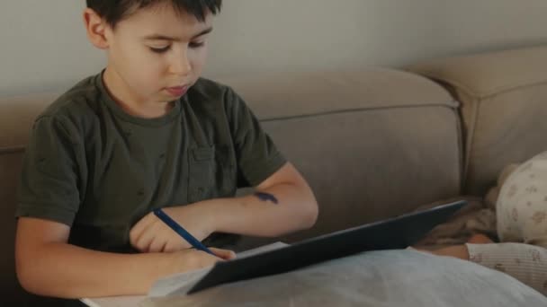 Lille Kaukasiske Dreng Fordybet Studere Sidder Sofaen Skrive Opgave Notesbog – Stock-video