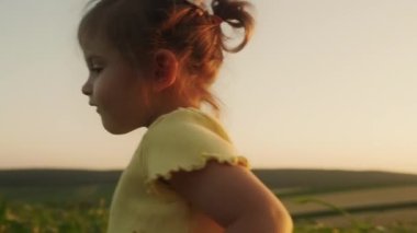 Sarı tişörtlü küçük kız yeşil mısırlarla tarlada yürüyor. Mutlu bir çocukluk, kırsal, köy hayatı, tatil kavramı..