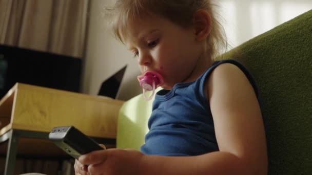 Menina Criança Chupando Uma Chupeta Enquanto Sentado Jogando Jogo Dispositivo — Vídeo de Stock