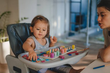 Güzel bebek evde tahta oyuncaklarla oynuyor. Bebekler renkli bir oyuncakla oynarlar. Çocuk gelişimi.