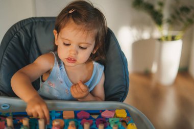 Masada ahşap çevre dostu numaralar, şekiller ve harflerle oynayan kız çocuğu. Entelektüel oyun. Erken gelişme.