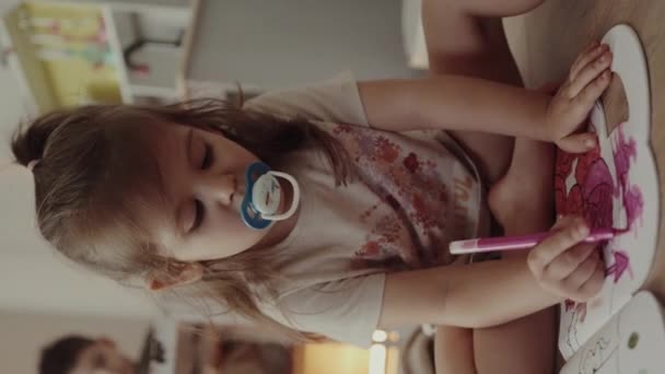 2歳の可愛い幼い幼児の少女は 自宅の子供部屋のアルバムにピンクのマーカーで描いた太鼓を吸っています 教育活動について — ストック動画