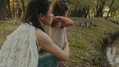 Anne ve küçük kızı yaz günü ördekleri besliyor. Çocuk dışarıda kuşları besliyor. Küçük çocuklar için yaz etkinliği.