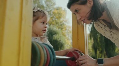 Genç bir anne kızına oyun alanında renkli abaküs kullanmayı öğretiyor. Çocuk gelişimi, çocuk eğitimi, bebek eğitimi