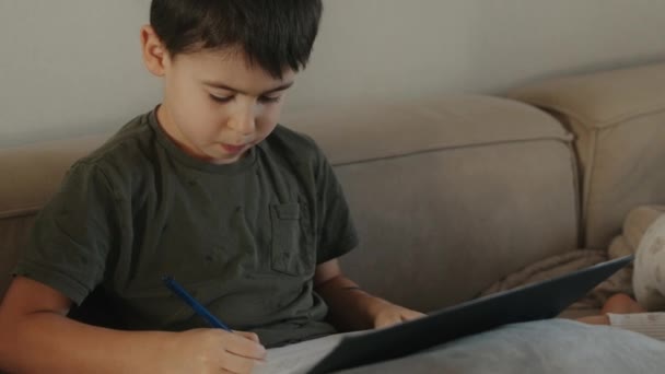Menino Adorável Sentado Sofá Escrevendo Caderno Com Caneta Dentro Conforto — Vídeo de Stock