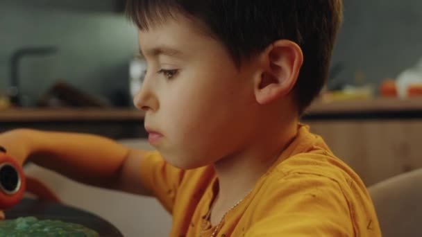 かわいい少年は テーブルに座っている車のおもちゃやキンクロサンドで遊ぶ自信があります 早期開発について 幼稚な男の子が車をやっている ファインモータースキルホームレジャー — ストック動画