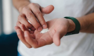 Beyaz kremalı şeker tutan erkek elleri. El çaresi. Kozmetik