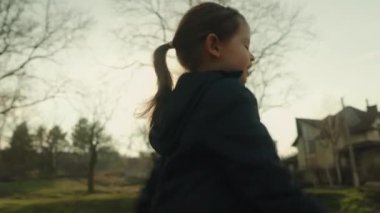 Sonbahar parkında koşan mutlu bir kızın yan görüntüsü. Çocuk sahada koşuyor. Doğada oynayan çocuk. Mutlu aile.