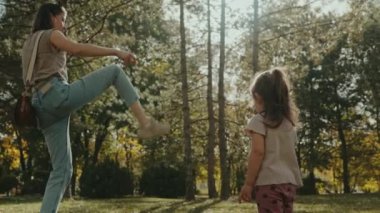 Anne kızıyla eğleniyor, ona çam kozalağını nasıl tekmeleyeceğini gösteriyor, yaz parkında birlikte oynuyorlar. Mutlu bir çocukluk kavramı. Mutlu bir aile...