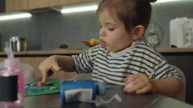 Sevimli küçük beyaz kız ailesine hediye olarak kart hazırlamaya çalışıyor. Sanat projesi