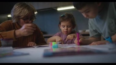 İki beyaz çocuk, erkek ve kız kardeş, tatilleri boyunca resim ve çizim yapıyorlar. Mutlu aile birlikte oynayarak vakit geçiriyor..