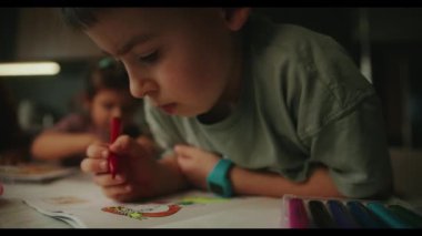 Masada renkli kalemlerle resim çizen sevimli küçük bir çocuk. Oyun okulundaki yaratıcı aktiviteler