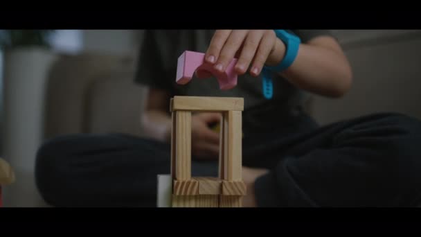 キッズハンドビルド要塞タワーアーキテクチャ木製レンガエコロジー材料 幼稚園で建設エコフレンドリーな虹レンガをプレイしている赤ちゃんの少年 — ストック動画