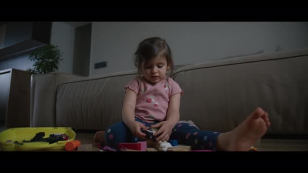 Skoncentrowana Dziewczynka Bawiąca Się Zabawkami Siedzącymi Ciepłej Podłodze Nowoczesnym Salonie — Wideo stockowe