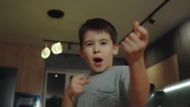 Sevimli çocuk hareketli hareketlerle ellerini kaldırıyor. Sıradan bir tişört giyiyorlardı. Kenara bak..