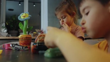 Küçük çocuk ve kız, mutfak masasında model araba koleksiyonuyla oynayıp ekmek yiyorlar. Çocuk odasında oyuncak dağınıklığı. Küçük çocuklar için bir sürü araba. Eğitici