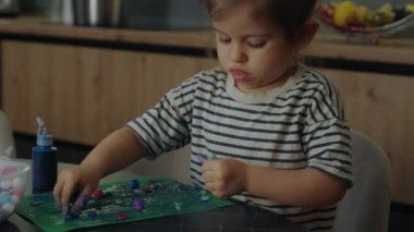 Yeşil kağıt renkli pamuk toplarına yapıştırılmış el sanatları ve el sanatları yapan kız çocuğu. Sanat ve zanaat zamanı.