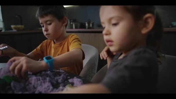 白人孩子在家里的桌子上玩彩色聚合物沙子 — 图库视频影像