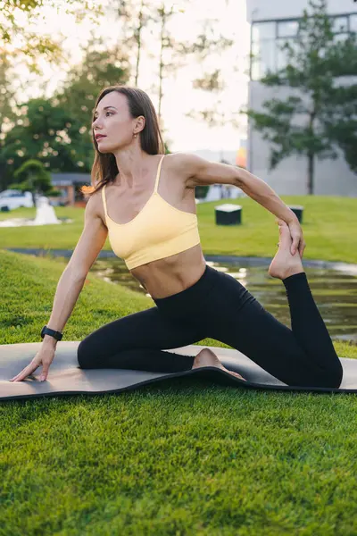 Dışarıda yoga yapan genç bir kadının yan görüntüsü. Yoga ve rahatlama konsepti. Güzel kadın yoga yapıyor.