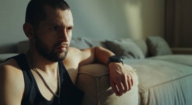 Ciddi bir yetişkin adam evde yerde oturuyor ve elini kanepeye yaslıyor. Depresyonda yalnız ve üzgün, akıl sağlığı yerinde. Yoğunlaştırılmış ciddi çekicilik