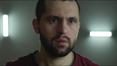 Sakallı yakışıklı bir erkek resmi, şaşırmış bir yüz ifadesi ve geniş açık gözleri ile karanlık oda arka planında izole..