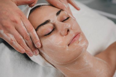 Güzellik salonundaki güzellik prosedüründen önce beyaz erkekleri temizleyen nitelikli bir güzellik uzmanı. Cilt temizleme spa rahatlama konsepti