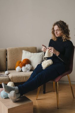 Genç kadın örgü kıyafetleri, sandalyede dinlenen bir kadın. Kız örgü örüyor. Örgü örüyorum.