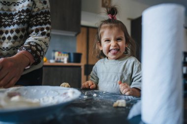Mutlu kız, yaşlı büyükannesiyle kurabiye bisküvileri pişiriyor. Mutfakta kameraya bakarak eğleniyorum..