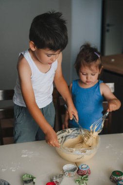 Kreş çocuğu hamuru karıştırıyor, kız da kâseye ilgi duyuyor. Kardeşler yemek pişirir. Erkek ve kız kardeş sürpriz yapıyor, ebeveynlere yardım ediyor. Aile, destek kavramı