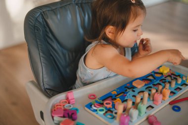 Küçük kız renkli oyuncak bloklarıyla oynuyor. Eko ahşap oyuncaklar. Küçük akıllı çocuk doğal oyuncaklar oynuyor. Erken gelişim oyunları.