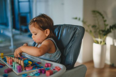 Küçük kız bebek masasında ahşap çevre dostu alfabe harfleriyle oynuyor. Entelektüel oyun. İlköğretim öncesi eğitim. Erken gelişme.