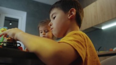 Küçük çocuk ve kız renkli araba oyuncaklarıyla oynuyorlar, birlikte ilginç bir eğitim aktivitesi yapıyorlar. İki çocuk, kız kardeş ve erkek kardeş oyuncaklarla eğleniyor.