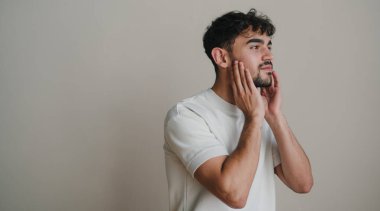 Beyaz arka planda kırışıklık önleyici bir maske takan mutlu bir adamın yan görünüm portresi. Erkekler için nemlendirici yüz kremi maskesi. Boş alan